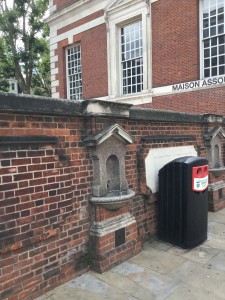 A black recycling bin blocking the view of a historical marker. (P. Ferguson image, August 2018)